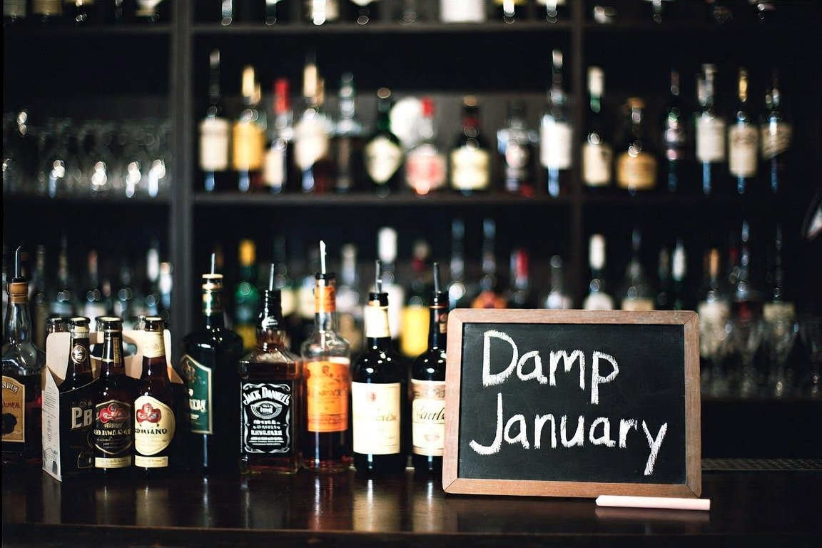 Damp January chalkboard on a bar with bottles behind it
